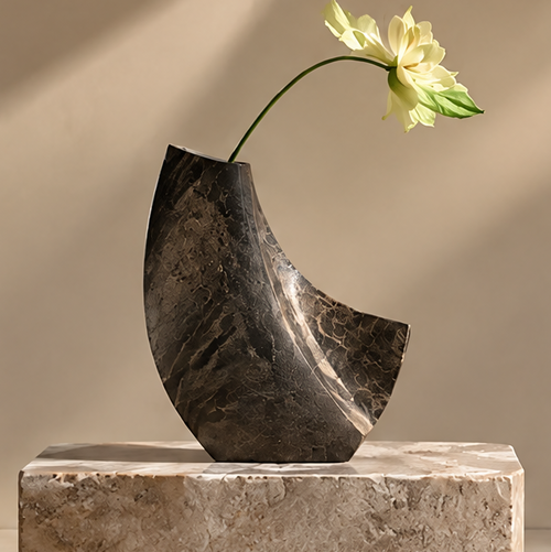 FORMIQI black marble crescent sculptural vase with yellow lotus on stone plinth, clean background